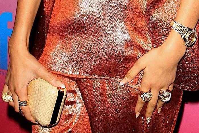 Closeup of Zendaya's assortment of John Hardy rings, Rolex watch, and beige Oroton "Odeion" clutch