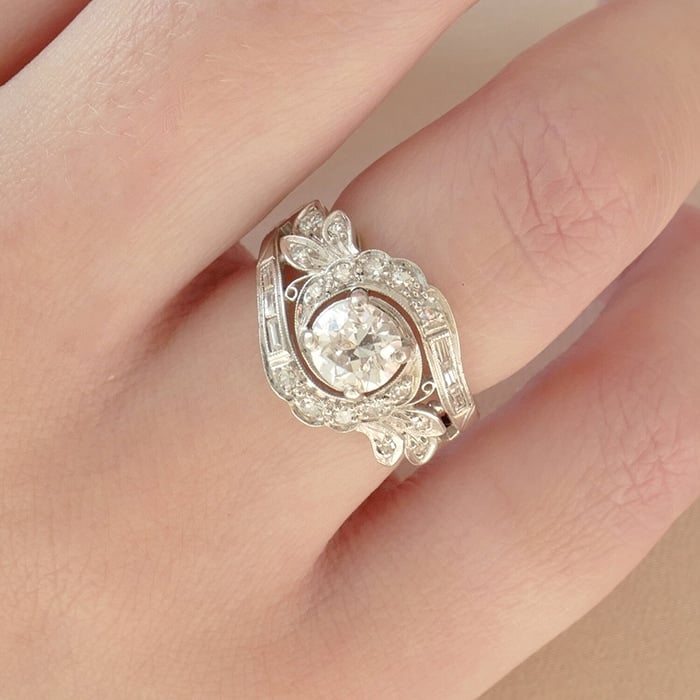 An Art-Deco engagement ring, the Gabrielle features a one-carat old European cut diamond with a mix of baguette and single cut diamonds in a floral swirl pattern