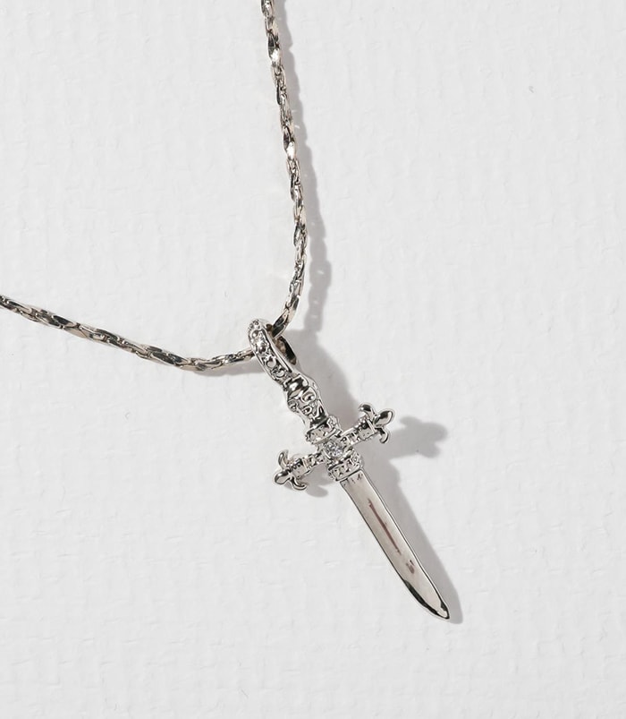 The Alexandra necklace features a lightweight dagger with a tiny skull, fleur-de-lis handles, and a crystal CZ in the center